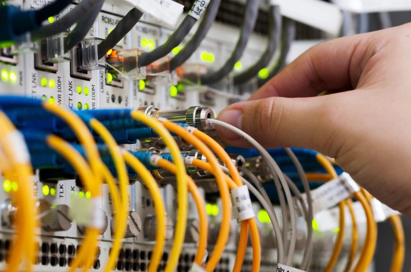 A person is working on some wires in the middle of a rack.